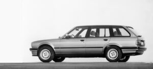 Silberner BMW Kombi seitlich, auf grauem Boden, vor weißem Hintergrund.