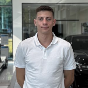 Mann im weißen Polohemd vor Autos in einem BMW-Autohaus.