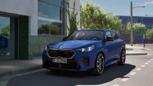 Blauer BMW X2 parkt auf einer sonnigen Straße vor einem modernen Gebäude mit Glasfassade.