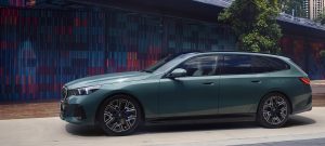 Grüner BMW Kombi vor bunter Wand mit geometrischem Muster, seitlich fotografiert.