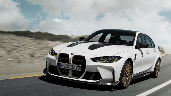 Weißer BMW M3 fährt dynamisch auf einer Straße, blauer Himmel im Hintergrund.