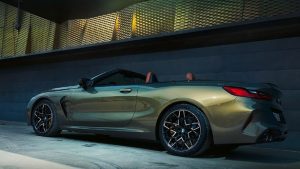 BMW 8er Cabrio in Metallicfarbe, seitliche Ansicht, geparkt vor moderner Gebäudewand.