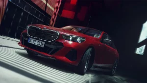 Roter BMW i5 M60 in einem dunklen Raum, schräg von vorne fotografiert.