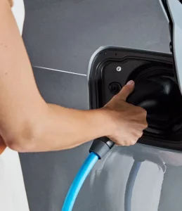 Person lädt Elektroauto mit blauem Ladekabel.