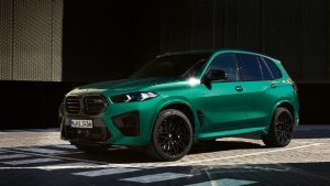 Grüner BMW X5M 2023 auf Asphalt, Seitenansicht, bei Tageslicht fotografiert.
