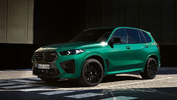 Grüner BMW X5M 2023 auf Asphalt, Seitenansicht, bei Tageslicht fotografiert.