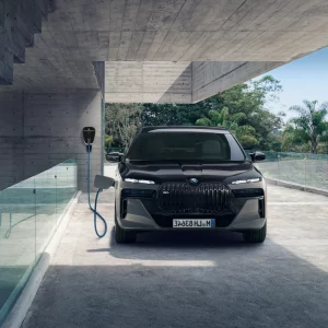 Schwarzer BMW lädt an einer Wallbox in moderner Garage mit Glaswand und Betonoptik.