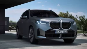 Silberner BMW SUV mit markantem Kühlergrill, parkend in moderner Umgebung bei Tageslicht.