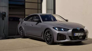 Grauer BMW i4 M50, seitlich aufgeladen, steht vor einem Gebäude bei Tageslicht.