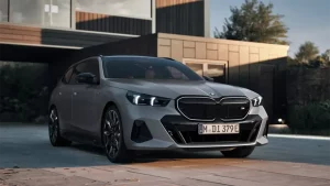 Silberner BMW Kombi vor modernem Haus bei Sonnenuntergang.