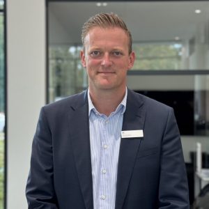 Ein Mann in Anzug mit Namensschild in einem modernen Büro.