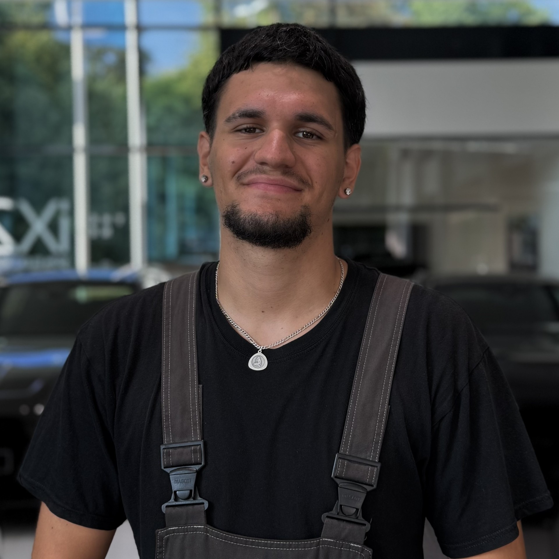 Ein Mann in weißem Polohemd steht in einem Autohaus, im Hintergrund ein schwarzes Auto.